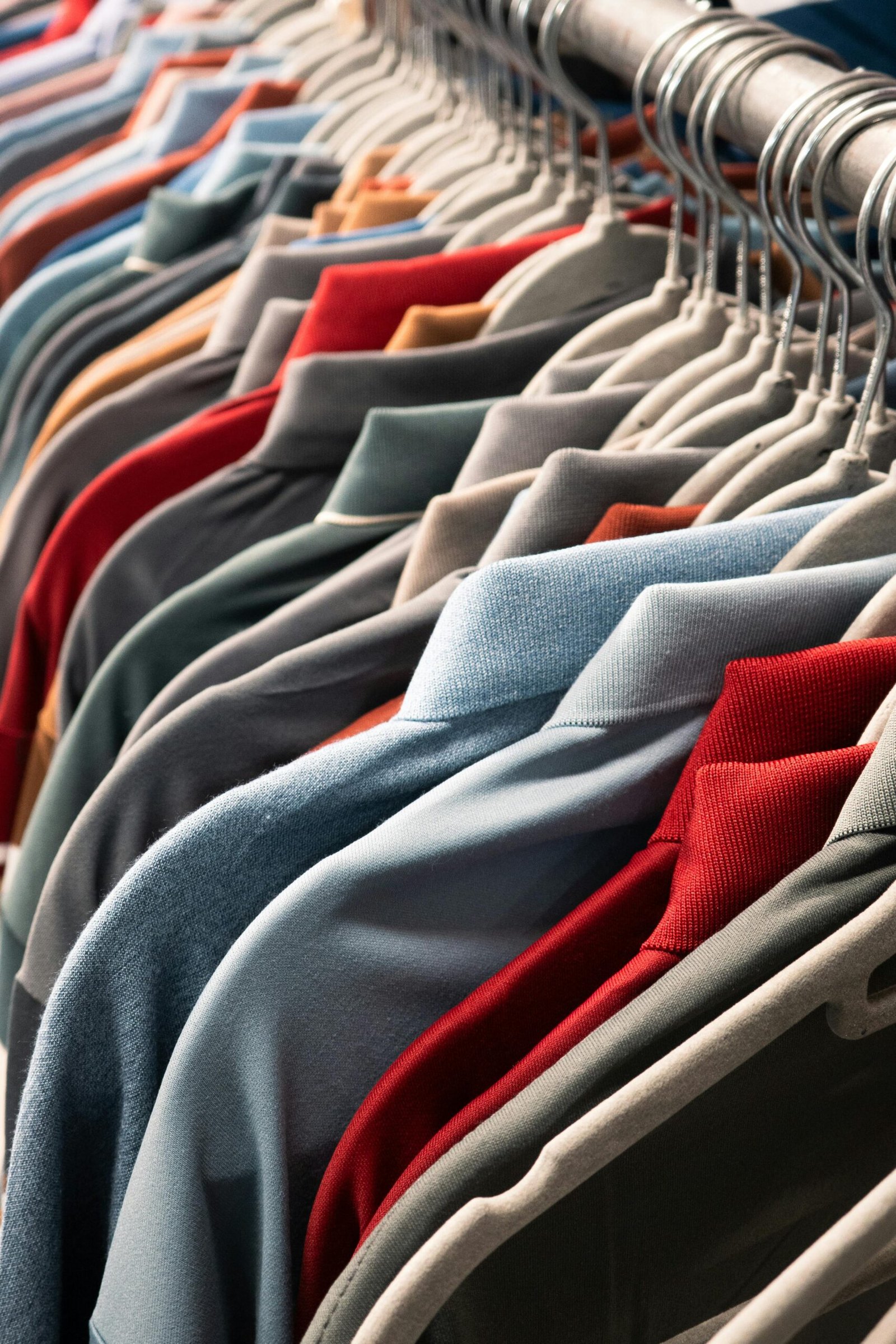 A vibrant row of various colored t-shirts neatly arranged on hangers in a store setting.